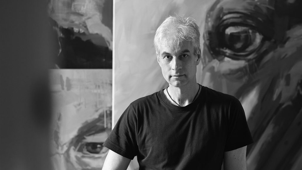 Der Pferdemaler Hartmut Hellner steht vor einigen Gemälden in seinem Atelier.