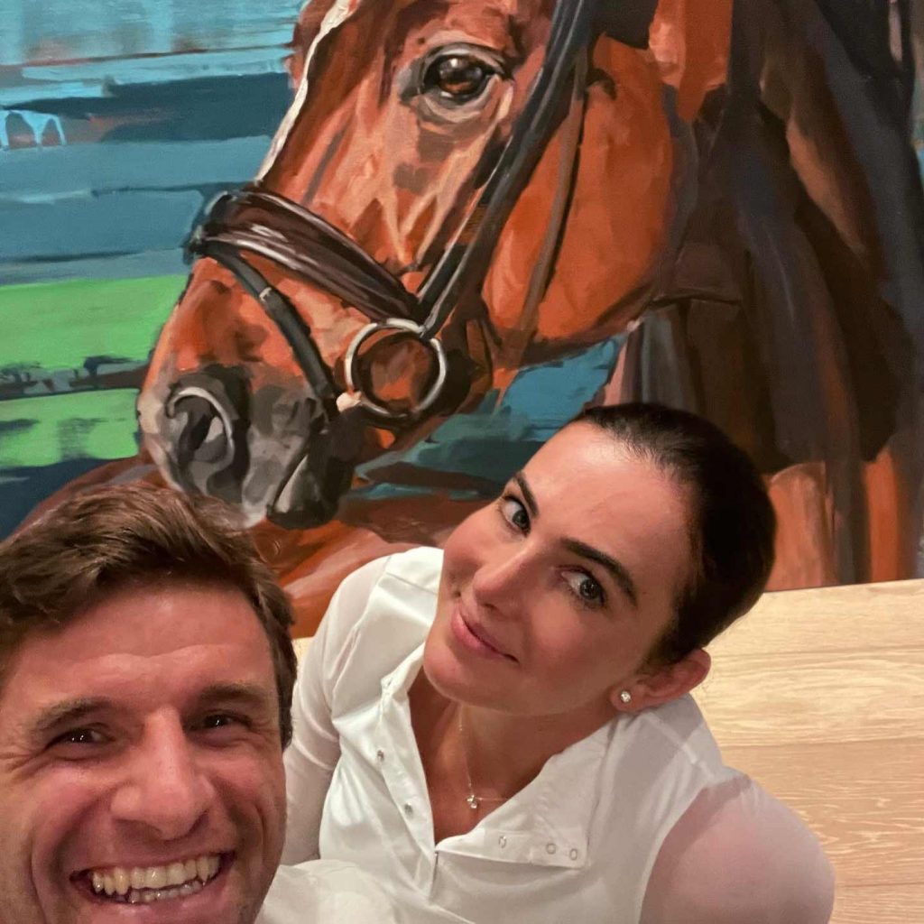 der Fußballstar Thomas Müller und seine Frau Lisa vor einem Porträt ihres Pferdes D'avie von Hartmut Hellner